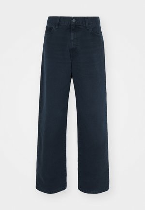 Tumesinine laiemad teksad, mis on valmistatud denimist, nuppude sulgemise ja vööristmikega. Omab kahte esimest taskut ja sileda, tekstuuriga viimistlust.