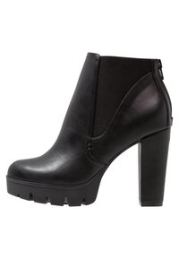 Stivaletto alla caviglia in pelle nera con una piattaforma importante e un alto tacco a blocco. Presenta pannelli laterali elasticizzati e una finitura testurizzata.