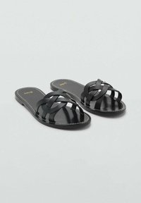 Sandale negre plate din piele netedă, cu design împletit al curelei, vârf deschis și o talpă subțire cu cusături minime.