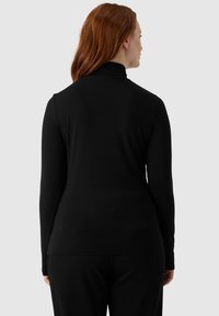 Maglia nera a maniche lunghe con collo a imbuto, realizzata in tessuto morbido, caratterizzata da un design aderente e una superficie liscia, vista da dietro.