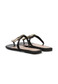 Sandalias planas negras con tiras finas y una pieza decorativa de metal dorado curvado en la parte frontal, mostradas lado a lado sobre un fondo blanco.