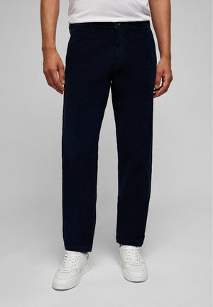 Donkerblauwe corduroy broek met een rechte pasvorm, voorzien van een knoopsluiting en een vijfzakkenontwerp, gecombineerd met witte sneakers.