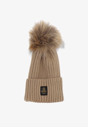 Berretto a maglia beige con una texture a costine, caratterizzato da un pompon in pelliccia sintetica sulla parte superiore e un'etichetta nera sul risvolto.