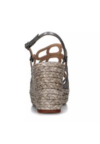 Sandalo con zeppa in juta intrecciata, dettagli metallici e design con schiena aperta. La parte superiore presenta motivi decorativi a taglio.