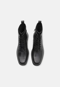Bottes chevilles en cuir noir avec une finition lisse, bout carré, chaussage à lacets à l'avant et détail de fermeture éclair sur le côté pour un enfilage facile.