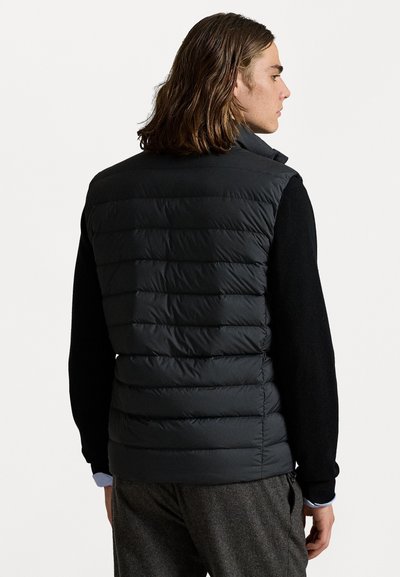 Sort puffer vest med quiltede sektioner. Høj krave, letvægtsdesign, velegnet til lag-på-lag over en langærmet bluse.