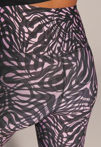 Högmidjade leggings med ett svart och rosa abstrakt mönster med en smidig textur. Sömdetaljer längs sömmarna förbättrar designen.