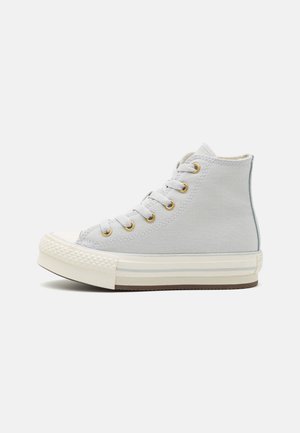 Sneaker alta in tela grigia con punta in gomma bianca, occhielli dorati e dettagli beige. Presenta suola testurizzata e lacci.