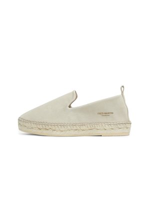 Zapato de ante beige sin cordones con diseño troquelado, detalles de cuerda de yute a lo largo de la suela y una pequeña lengüeta en el talón. Logo grabado en el lado.
