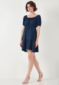 Navy blue, short-sleeve dress with a square neckline, gathered bodice, and tiered skirt. Lightweight fabric with a soft texture.