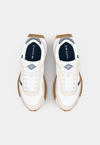 Sneakers met een witte synthetische bovenkant, beige accenten en een marineblauwe streep. Voorzien van witte veters, rubberen zool met een textuur voor grip. Klassiek logodetail.