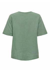 Top verde a maniche corte con un motivo testurizzato e stropicciato. Presenta un collo rotondo e una vestibilità morbida con un orlo leggermente curvo.