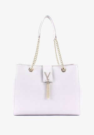 Bílá kabelka s texturou a strukturovaným tvarem, dvojitými zlatými řetízkovými popruhy, zlatou sponou a dekorativním třásňovým prvkem.