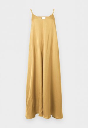 Ilga be rankovių garstyčių geltonumo satino suknelė su plonomis petnešėlėmis ir laisvu, plačiai krentančiu siluetu, kabanti ant vienspalvės sienos.