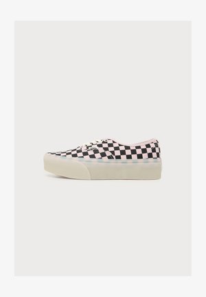 Baskets basses Vans avec motif à carreaux noir et rose et semelle épaisse en caoutchouc blanc, vues de profil sur fond blanc.