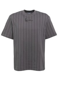 Grå t-skjorte med korte ermer, tynne svarte vertikale striper og en liten svart brodert signatur nær halsåpningen.