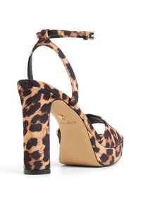 Sandalia de tacón alto con estampado de leopardo, correas negras, suela con plataforma y tacón grueso. Detalle de herrajes dorados cerca del tacón.