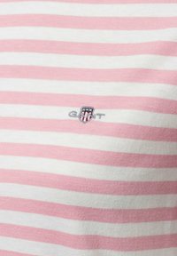 Gestreiftes T-Shirt aus weicher Baumwolle mit pinken und weißen horizontalen Streifen. Verfügt über ein kleines gesticktes Logo in Grau und Blau.