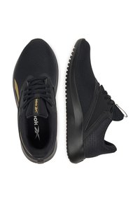 Pár čiernych športových tenísk z mrežoviny s čiernymi šnúrkami, čiernymi podrážkami a jemnými zlatými brandingovými detailmi na bielom pozadí.