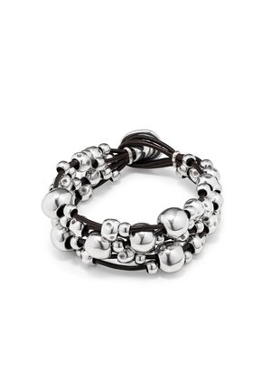 Pulsera de cuero negro de varias hebras con cuentas plateadas brillantes agrupadas de diferentes tamaños, dispuestas en un lazo con cierre anudado.