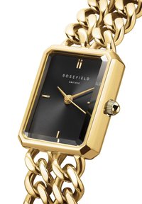 Gouden rechthoekige horloge met een robuuste schakelhalsband, zwarte wijzerplaat met cirkelpatroon, en gouden wijzers en indexen. Merkl logo zichtbaar.