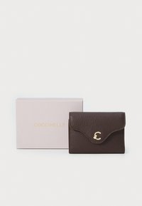 Portafoglio in pelle marrone con texture, chiusura a pattina e accento del logo dorato. Include una scatola rosa coordinata con il nome del marchio in lettere dorate.