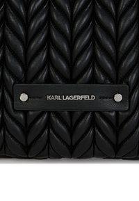 Sac à main en cuir matelassé noir avec un design tressé, une texture lisse et une plaque logo en métal argenté.