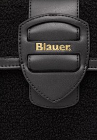 Matériel noir avec une finition texturée, présentant une sangle centrale en cuir noir et un détail du logo doré "Blauer.". Des accents de couture sont visibles.