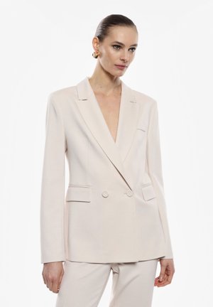 Blazer beige doppiopetto con rever a punte, due tasche frontali e bottoni, realizzato in un tessuto liscio, abbinato a pantaloni coordinati.