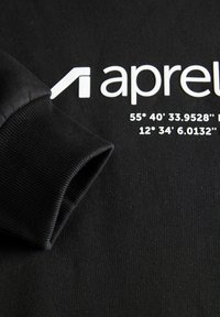 Zwarte sweatshirt met geribbelde manchet, voorzien van een wit logo en geografische coördinaten gedrukt in het wit nabij het midden.