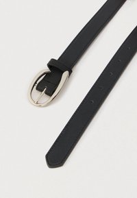 Sort læderbælte med sølv ovalt spænde, med flere justeringshuller og syede kanter på en lys baggrund.