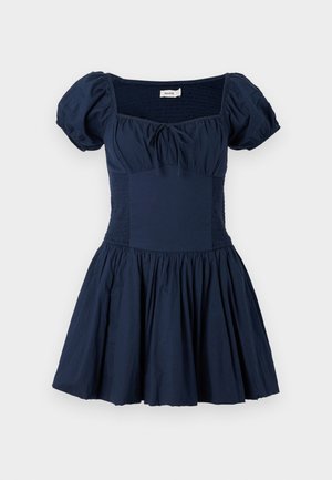 Rochie albastră închis cu mâneci bufante, decolteu pătrat și bust plisat. Fustă evazată cu material adunat, fabricată dintr-un material ușor din bumbac.