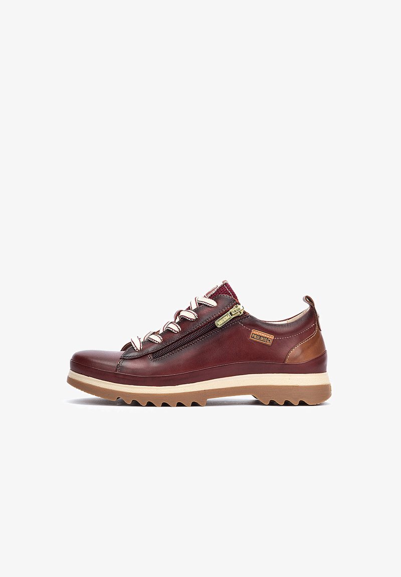 Zapato de cuero burdeos con detalles en marrón claro, cierre de cremallera y cordones blancos. Suela texturizada con profundos surcos para una mejor tracción.