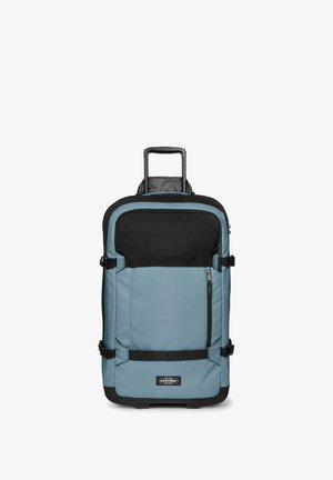 Bolsa de viaje azul y negra con ruedas, asa extensible, bolsillo frontal con cremallera, correas de compresión laterales y logo de Eastpak en la parte frontal inferior.