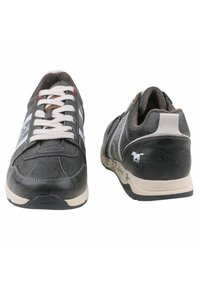 Baskets noires avec des accents beiges, design à lacets, détails cousus et un graphique de cheval sur le côté. Semelle en caoutchouc avec finition texturée.