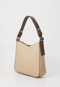 Beige läderaxelväska med en kurvig silhuett, brun accentrem, silverfärgad hårdvara och vit sömdekor.