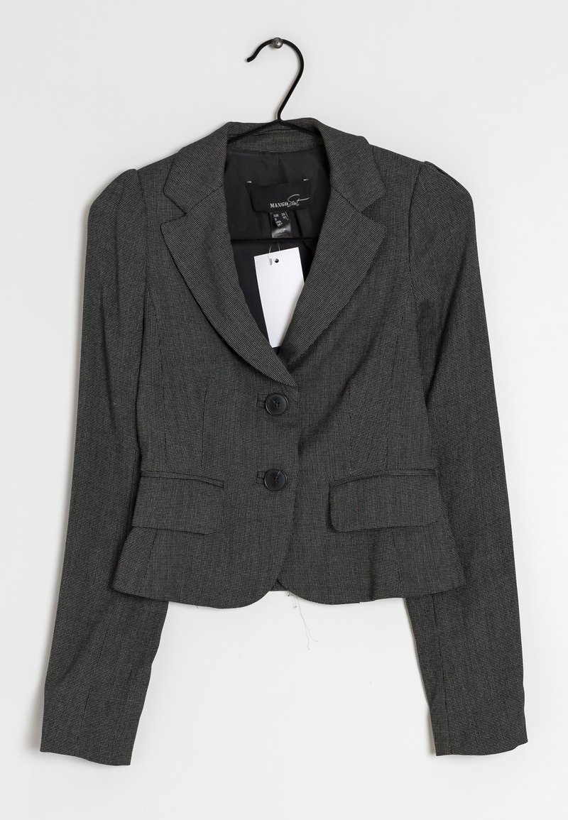 Blazer fitted gris foncé avec deux boutons, poches à rabat et une étiquette blanche accrochée au col sur un cintre noir sur un fond blanc.