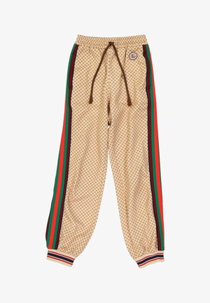 Pantalon de survêtement beige à motifs avec bandes latérales rouges, vertes et noires, cordon marron, poignets élastiques et logo rond à l'avant de la taille.