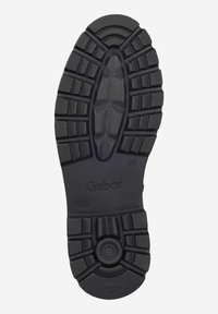 Suola di scarpa in gomma nera con motivo a battistrada texturizzato, caratterizzata da scanalature profonde per la trazione e un marchio impresso. Adatta a varie superfici.