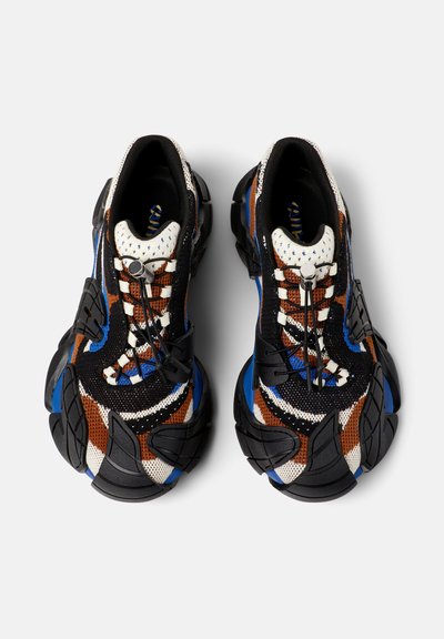 Voluminöse Sneaker mit einem schwarzen, braunen und blauen gestrickten Obermaterial. Strukturierte Gummisohle, innovatives Schnürsystem und gepolsterte Zunge.