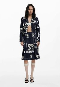 Marineblaues Jacken- und Rock-Set mit Zeitungsdruckmuster, aus Baumwollmaterial, figurbetontem Design, mit geschichteten Falten, präsentiert eine verkürzte Silhouette.