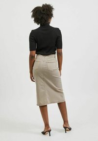 Béžová džínsová midi sukně s zadními kapsami, vysokým pasem a rozparkem, spárovaná s černým krátkým rukávovým ribbed topem a černými lodičkami.