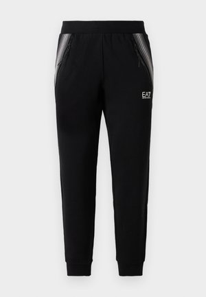 Crne taperirane trenirke s patentnim bočnim džepovima, ukrasnim trakama, elastičnom strukom i EA7 Emporio Armani logotipom na desnom butu.