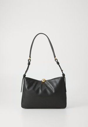 Bolsa de couro preta com uma base arredondada, textura suave, silhueta estruturada e fecho frontal com um detalhe em forma de bola dourada.