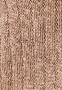 Tejido de punto en un color marrón claro con textura de canalé vertical. Material suave de peso medio con sutiles variaciones y una apariencia acogedora.