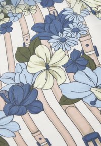 Material textil floral cu flori albastre și crem pe un fundal alb, cu bretele bej deschis, detalii intricate �și o textură netedă.