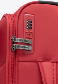 Roter Handgepäckkoffer aus strapazierfähigem Material, mit doppelt zip-verschluss und markierten Reißverschlüssen sowie einem integrierten Zahlenschloss an der Seite.