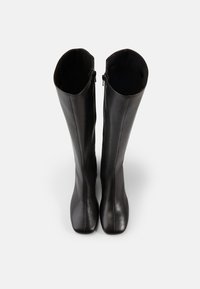 Aukšti juodos odos batai su lygiu paviršiumi, apvalia nosimi ir šoninėmis užtrauktukais. Vidaus dizainas švarus ir minimalistinis.