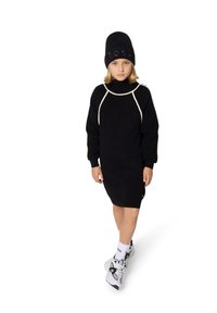 Robe en maille noire avec texture côtelée, dotée d'un col montant et d'accents blancs contrastants. Assortie à un bonnet noir et des baskets blanches sportives.