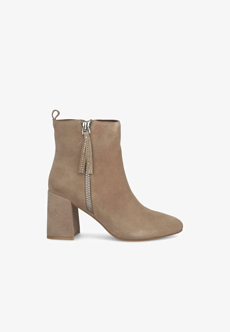 Botín de ante en beige claro con punta afilada, tacón cuadrado y cremallera plateada con detalle de borlón. Textura suave y diseño minimalista.